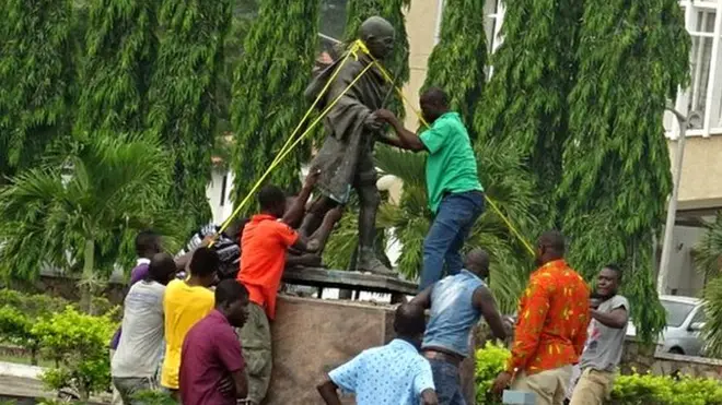 Люди демонтируют статую Махатме Ганди