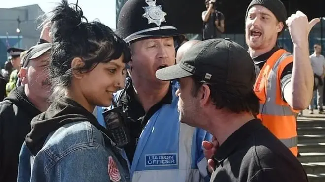 تلخ کلامی کا جواب مسکراہٹ کے ساتھ دیتے ہوئے یہ تصویر پریس ایسوسی ایشن کے فوٹو گرافر نے برمنگھم سکوائر میں سنیچر کو لی جو وائرل ہو گئی