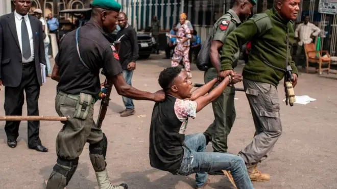 Police officers dey drag suspected criminals