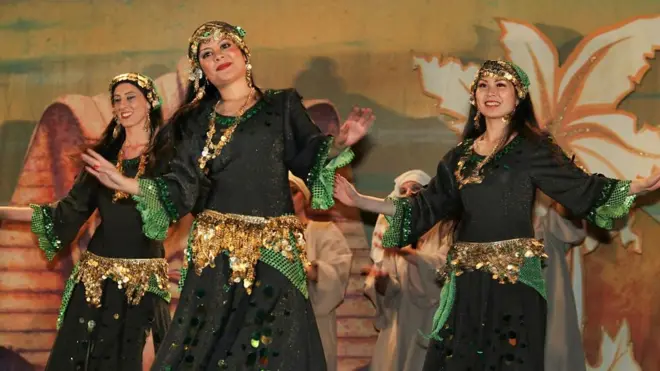 Three women dancing in local suits