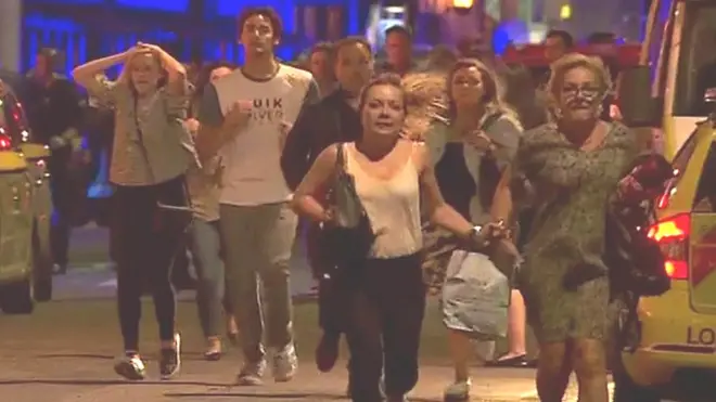 People fleeing with hands on their heads