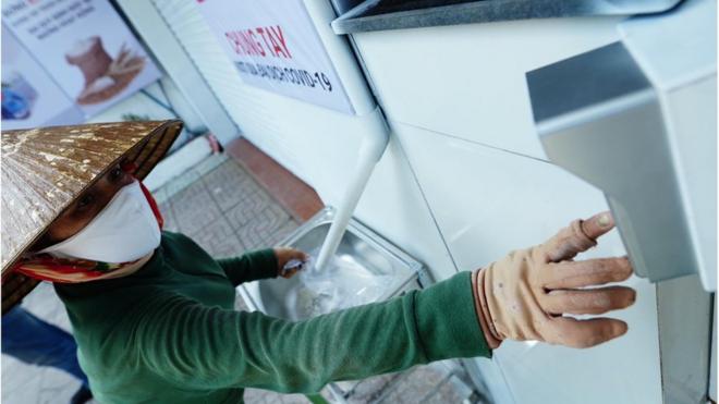 A woman keys in her details to collect rice from a "rice ATM".