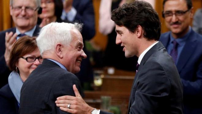 Canada's Prime Minister Justin Trudeau (R) shakes hands with former Immigration Minister John McCallum