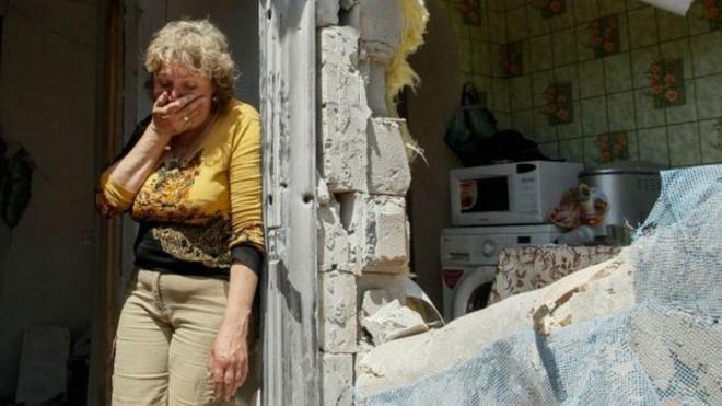 Жінка біля зруйнованого будинку