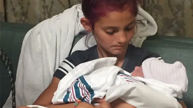 Jacee menggendong adik laki-laki yang baru saja dia bidani.