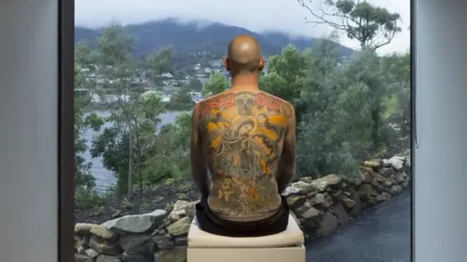 画展。山水风景是窗外的真实世界，男子背上的纹身才是展出的作品，作品名叫TIM。