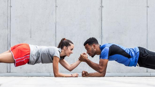 Un hombre y una mujer haciendo un ejercicio de resistencia de peso.