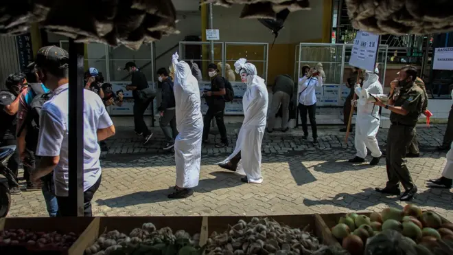Petugas Satpol PP Kecamatan Larangan mensosialisasikan penggunaan masker dengan menggunakan kostum hantu pocong di Pasar Kreo, Kota Tangerang, Banten, Rabu (16/09)>
