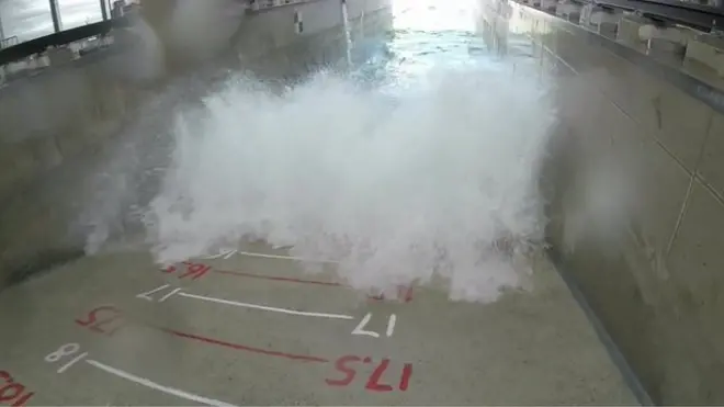 Wave crashing on wall with measuring scale