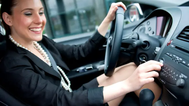 Женщина крутит ручку настройки радио в автомобиле