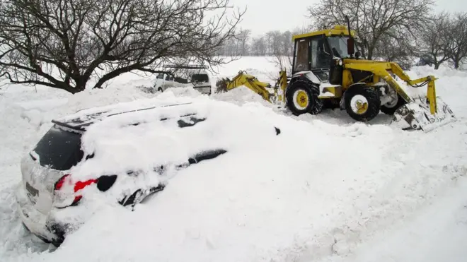Трактор розчищає сніг біля засипаного снігом автомобіля на автотрасі Одеса - Іллічівськ, 2009р.