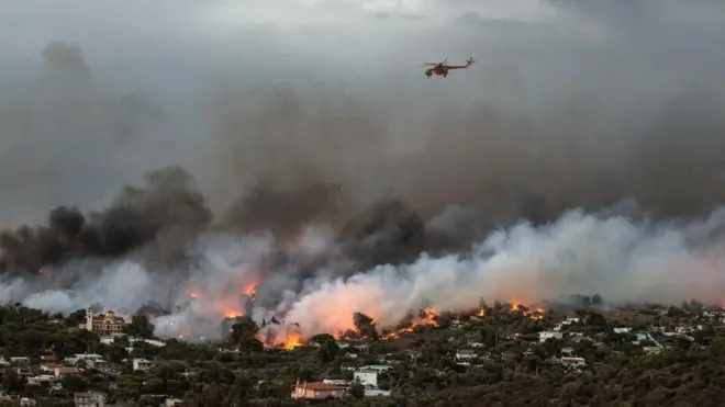 A firefighting helicopter flies over the town of Rafina on Attica's eastern coast, where fires are a recurring problem in the summer