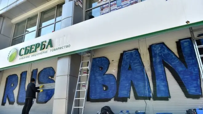 Прибиральник змиває надпис "Русбанк" залишений супротивниками торгівлі з Росією на будівлі "Сбербанку" в Києві