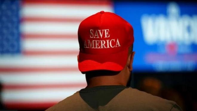 شخص يرتدي قبعة عليها كلمة أنقذوا أمريكا