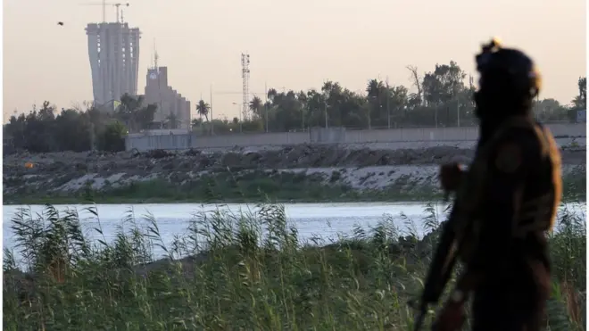 (أرشيف) أحد أفراد الأمن العراقي وفي الخلفية المنطقة الخضراء التي توجد بها السفارة الأمريكية