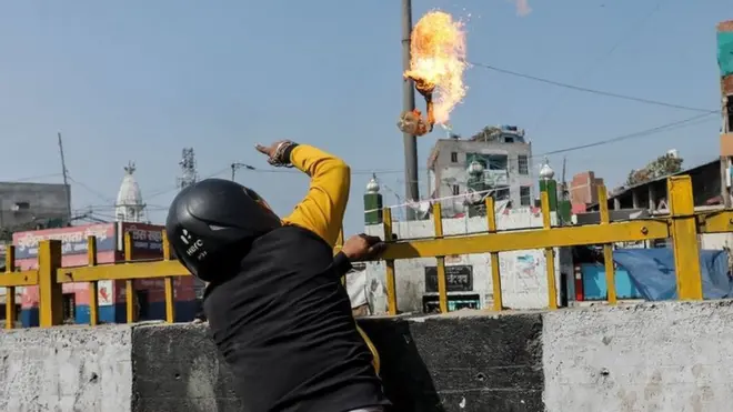 आग लगी चीज़ फेंकता एक शख़्स