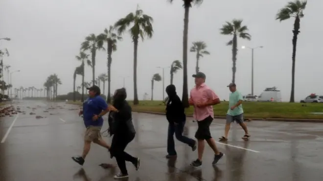 People race across the street as winds from Hurricane Harvey escalate in Corpus Christi, Texas