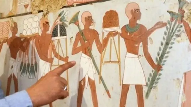 وزارت نوادرات کے اہلکار مقبرے کے اندر دیوار پر بنی رنگین پینٹنگ دکھا رہے ہیں