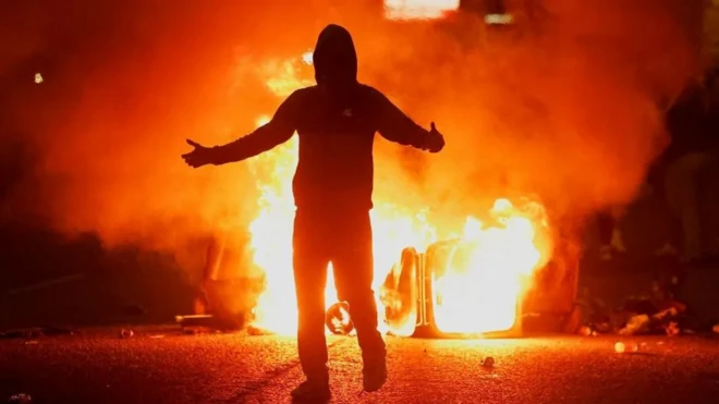 Силуэт участника беспорядков на фоне пламени