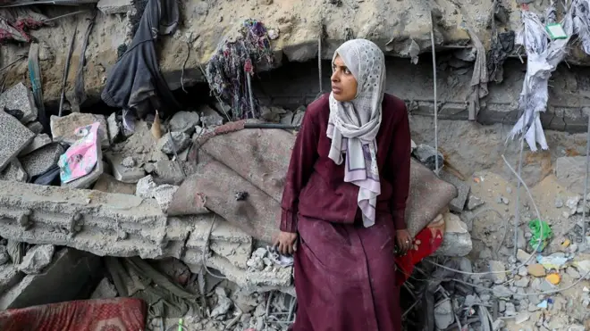 Palestinska žena sedi na ruševinama