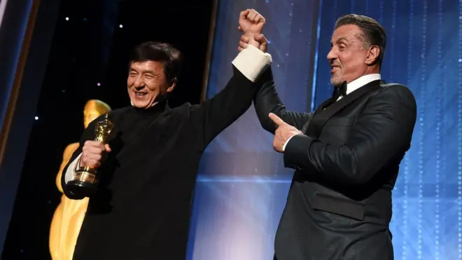 Jackie Chan receives his award from Sylvester Stallone