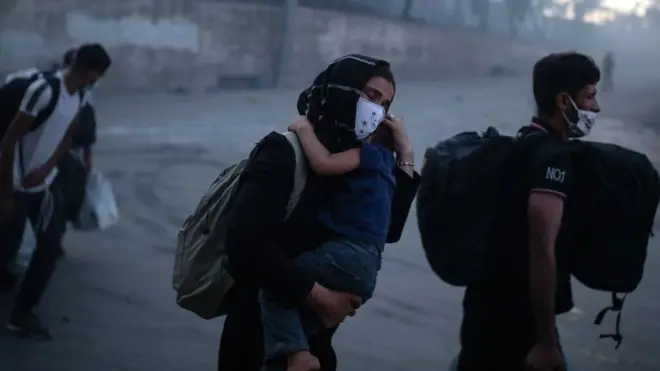 一位女士抱着一名男童逃离莫里亚营地（9/9/2020）