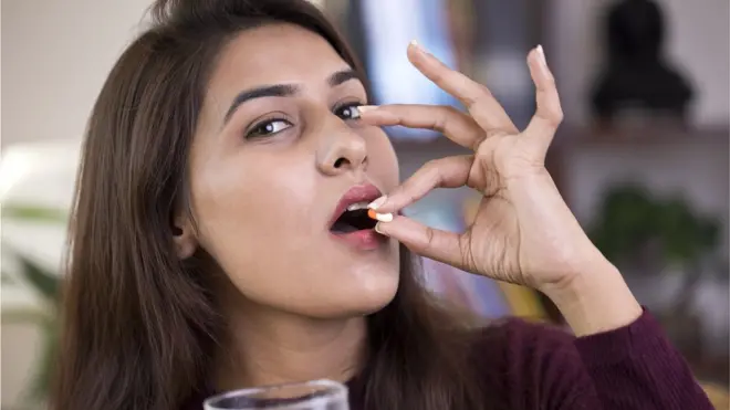 టాబ్లెట్ వేసుకుంటున్న భారతీయ మహిళ