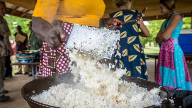 Du riz jeté dans un pot par une femme à Ganta, au Libéria