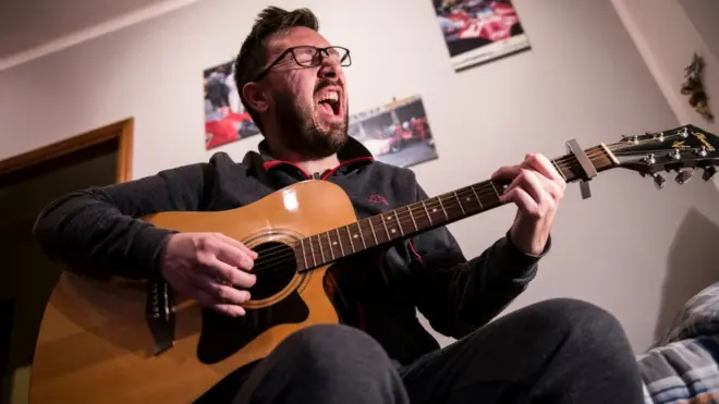 Житель Турина играет на гитаре дома