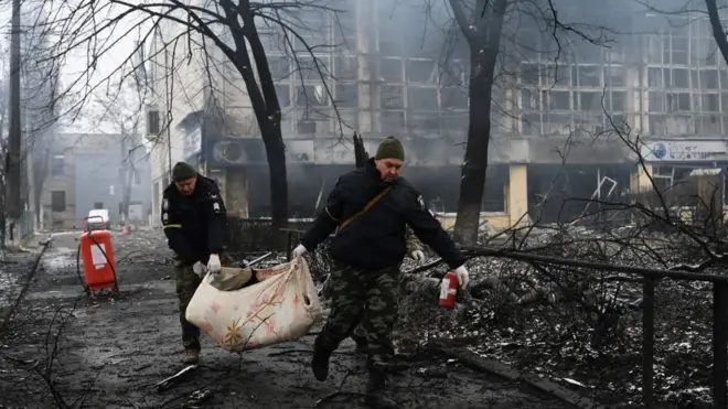 कीएव में हवाई हमले में मारे गए पदयात्री का शव ले जाते पुलिसकर्मी