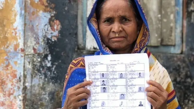 A woman holds up a draft list of the National Citizen's Register in Assam