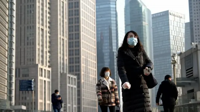 People wearing protective face masks walk on an overpass in Shanghai on February 24, 2020