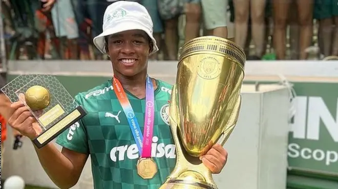 Endrick poses for a picture with two trophies