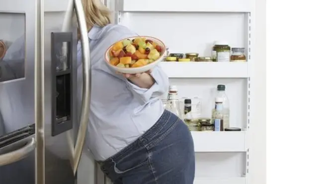 Una mujer busca comida dentro de una nevera