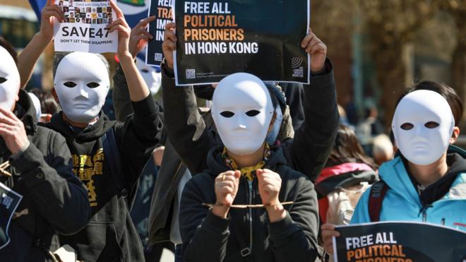 Demonstrators wear masks while holding placards during the protest . Hong Kong people in the UK stand silently in support of Hong Kong 47 case. The Hong Kong 47 are the 47 pro-democracy advocates of Hong Kong who, in February 2021, were charged with conspiracy to commit subversion under the Hong Kong national security law