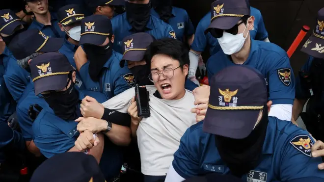 متظاهر محتجز بعد محاولته اقتحام السفارة اليابانية بسبب بدء طوكيو إطلاق المياه المشعة المعالجة من محطة فوكوشيما للطاقة النووية إلى المحيط الهادئ، في سيول، كوريا الجنوبية، 24 أغسطس 2023.