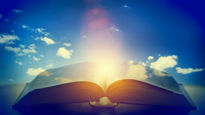 Libro abierto con una luz en el medio.