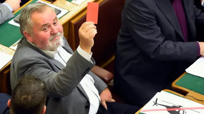 Sosyalist Parti'nin milletvekillerinden Zoltan Gogos oylama sonrası cebinden çıkardığı kırmızı kartı gösteriyor