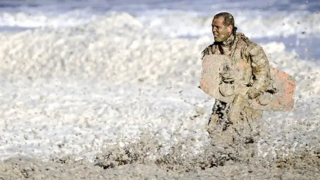 A rescue worker stands in rough waters during the resumed search for missing water sports participants in The North Sea at Scheveningen