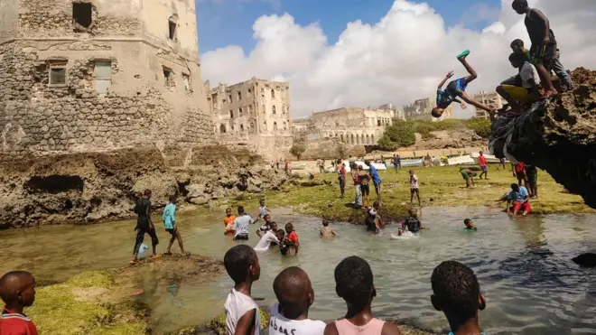 Caruur Soomaali ah oo ku dabaalanaya xeebta Xamarwayne, dhismo ayaa ka muuqdo dhanka kale, waxaa la qaaday Jimcihii