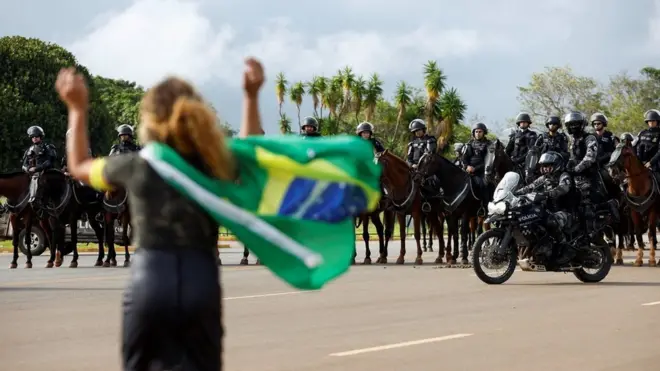 A demonstrator gestures towards members of security forces as supporters of Brazil's former President Jair Bolsonaro leave a camp outside the Army Headquarters, in Brasilia, Brazil, 9 January