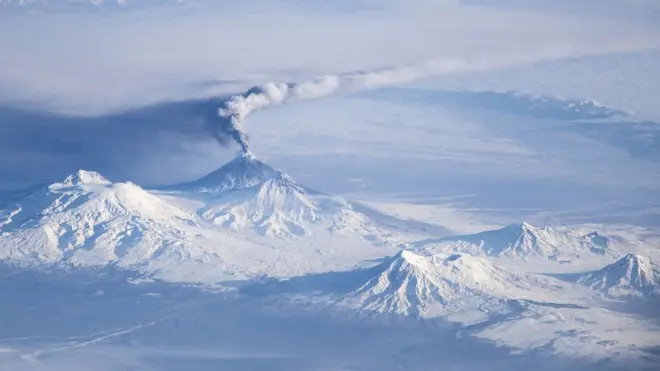 El Udina es uno de los volcanes de Península Kamchatka y está cercano al Kliuchevskoi (del que emana una columna de humo en la foto)