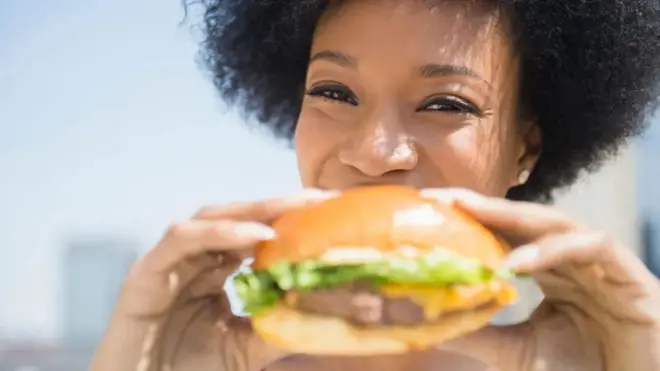 Une femme mangeant un hamburger.