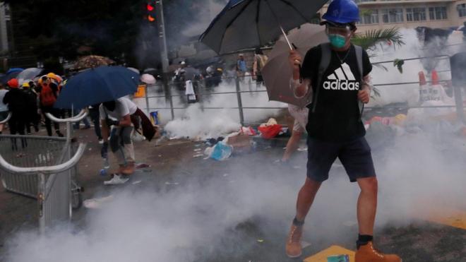A protester reacts to a tear gas during a demonstration against a proposed extradition bill in Hong Kong, China June 12, 2019