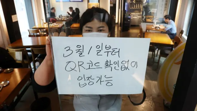 28일 서울의 한 식당 입구에 식당 관계자가 오는 3월 1일부터 시행되는 방역패스 적용 일시 중단 관련 안내문을 부착하고 있다