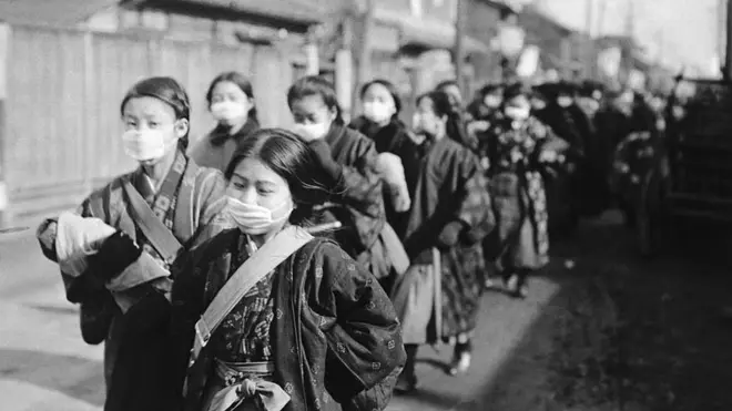 جاپان میں سکول کی طالبات 1920 میں سکول جاتے ہوئے ماسک پہنے ہوئے ہیں۔ 1918 کی فلو کے بارے میں اندازہ ہے کہ اس نے دنیا کی ایک تہائی آبادی کو متاثر کیا