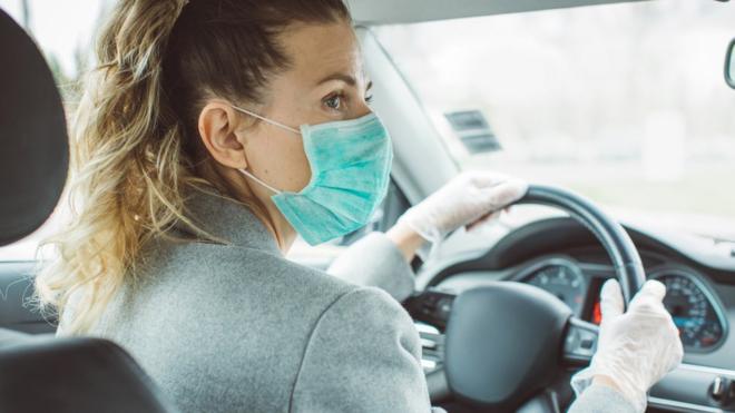 Woman wearing a face mask, driving a car