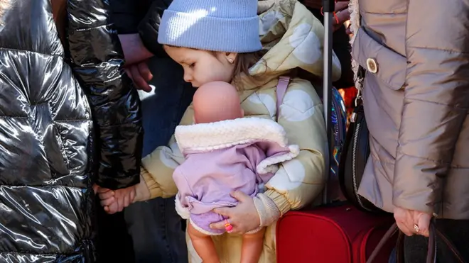 طفلة صغيرة تمسك بيد سيدة وتحتضن دمية في أوزهرود فايزن نيميك على الحدود الأوكرانية السلوفاكية