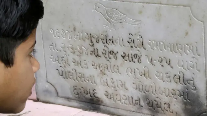 સ્મારકની તખ્તી વાચતો બાળક