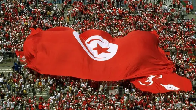 جماهير تونس ترفع علماً وطنياً ضخماً، خلال مباراة فريقها ضد فريق إنجلترا في كأس العالم 1998